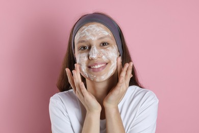 Photo of Teenage girl with cream on her face against pink background. Acne treatment