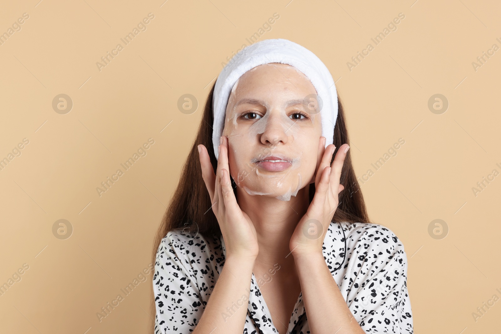 Photo of Teenage girl with sheet facial mask on beige background. Acne treatment