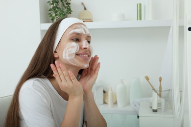 Photo of Teenage girl with cleansing foam on her face at home. Acne treatment