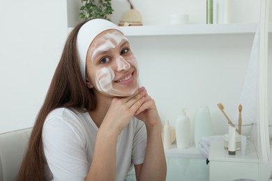 Photo of Teenage girl with cleansing foam on her face at home. Acne treatment