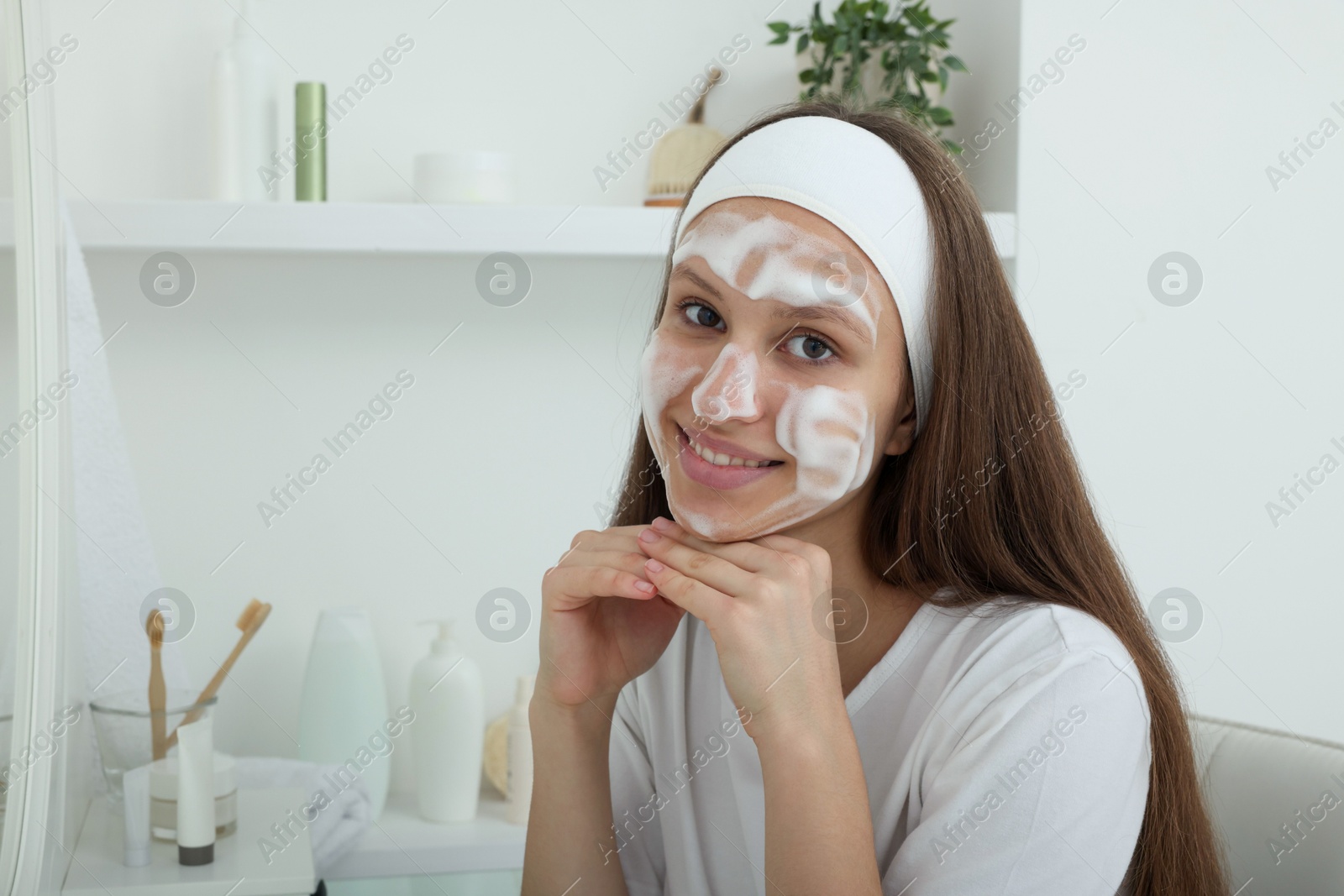 Photo of Teenage girl with cleansing foam on her face at home. Acne treatment