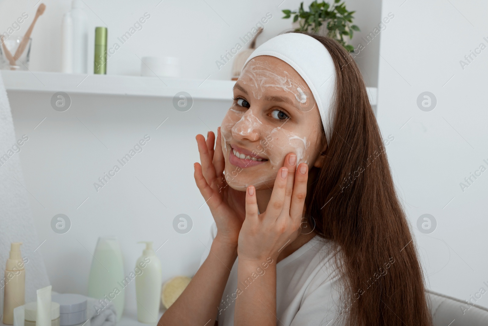 Photo of Teenage girl applying cream onto face at home. Acne treatment