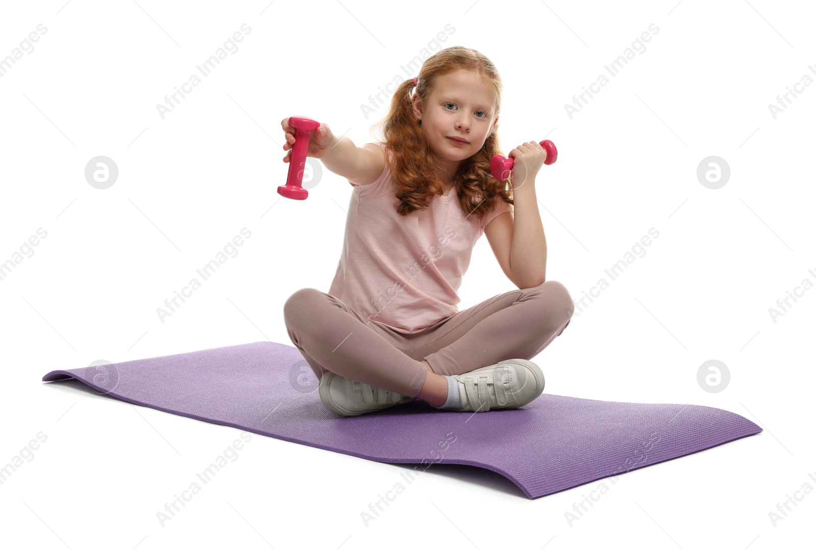 Photo of Cute little girl with dumbbells and fitness mat on white background