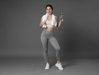 Photo of Woman in sportswear with bottle of water and towel on grey background