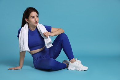 Photo of Woman in sportswear with towel on light blue background, space for text