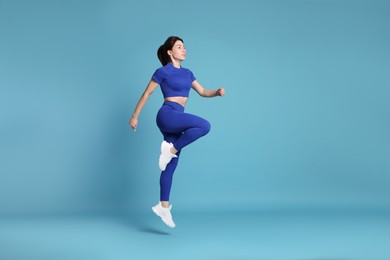 Photo of Woman in sportswear exercising on light blue background