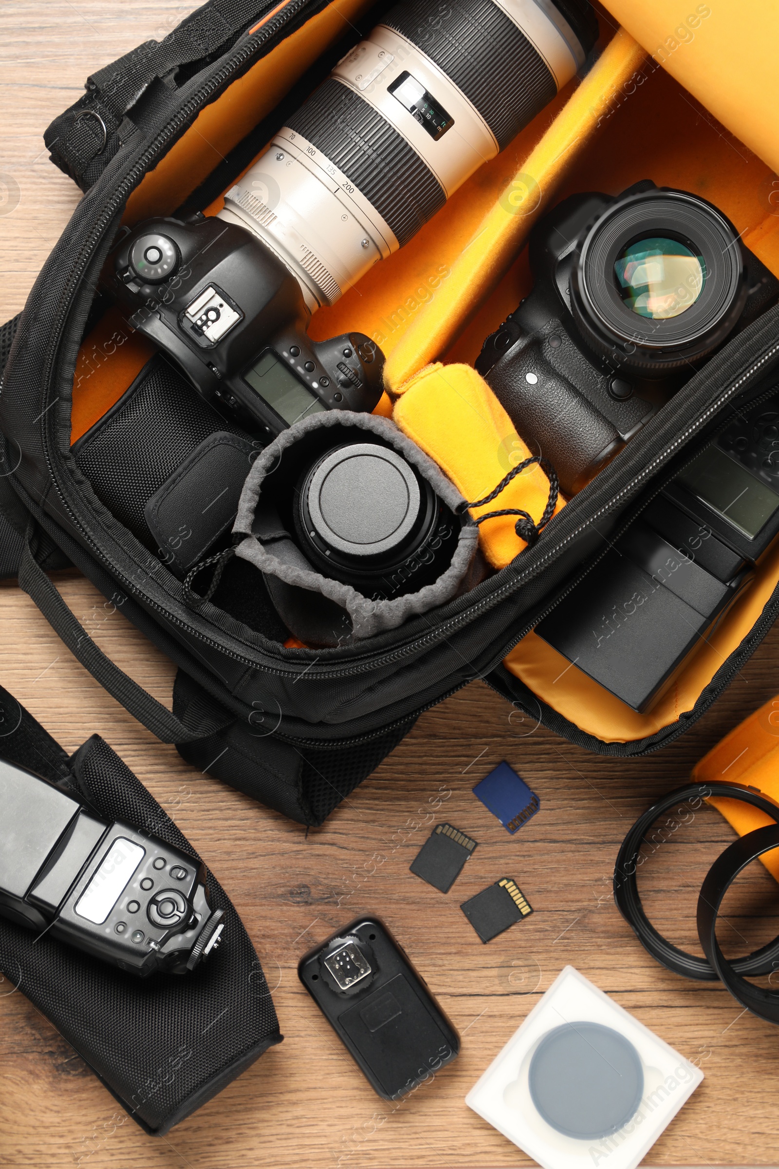 Photo of Professional photographer's equipment and backpack on wooden background, flat lay