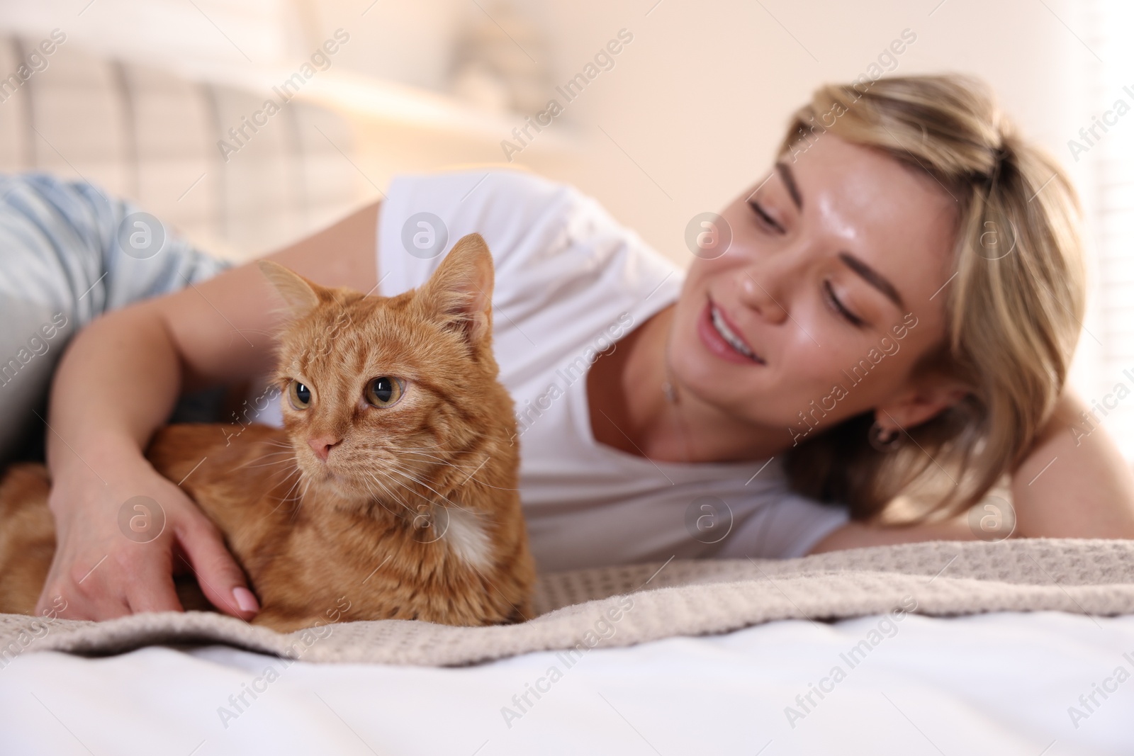 Photo of Woman with her cute ginger cat on bed at home, selective focus