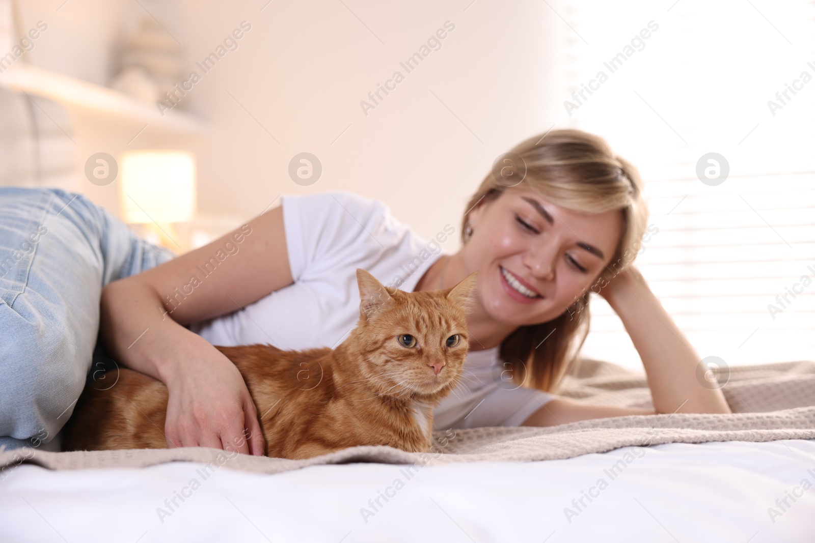 Photo of Woman with her cute ginger cat on bed at home, selective focus