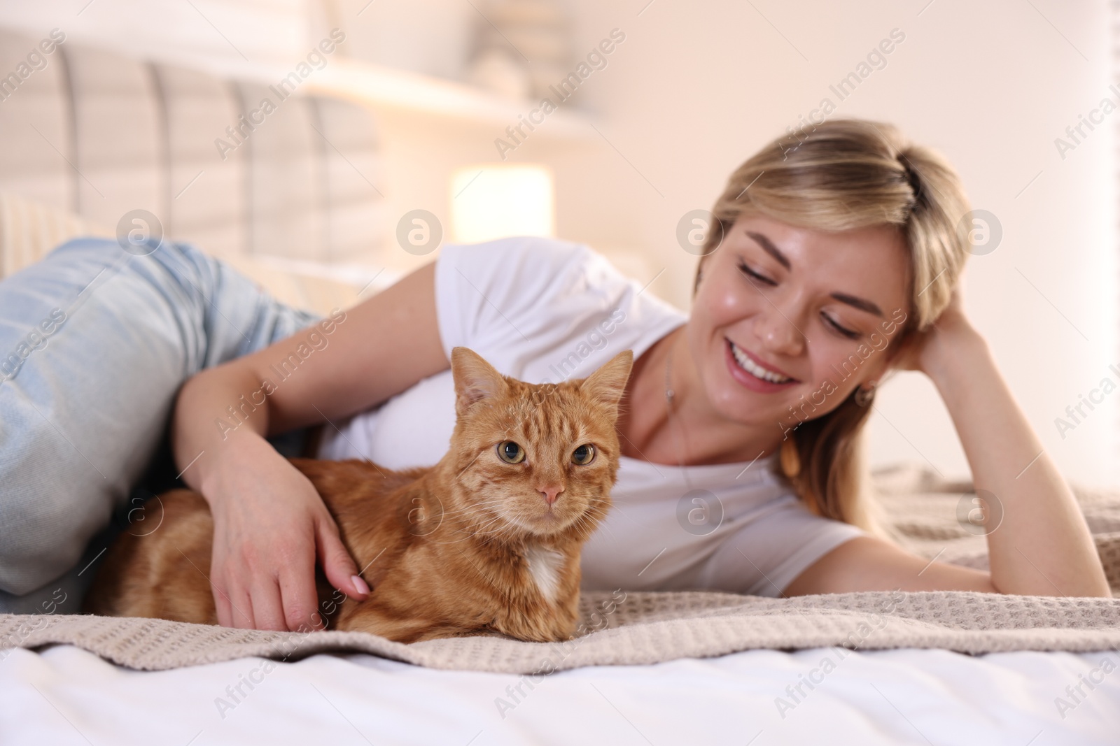 Photo of Woman with her cute ginger cat on bed at home, selective focus