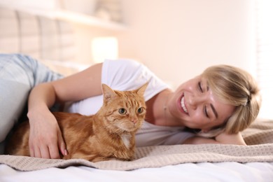 Photo of Woman with her cute ginger cat on bed at home, selective focus