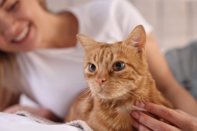 Photo of Woman with her cute ginger cat on bed at home, closeup