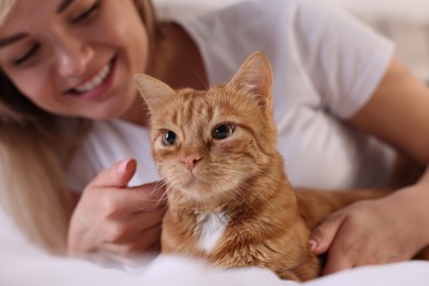 Photo of Woman with her cute ginger cat at home, selective focus