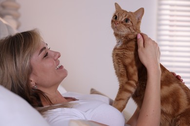 Photo of Woman with cute ginger cat at home