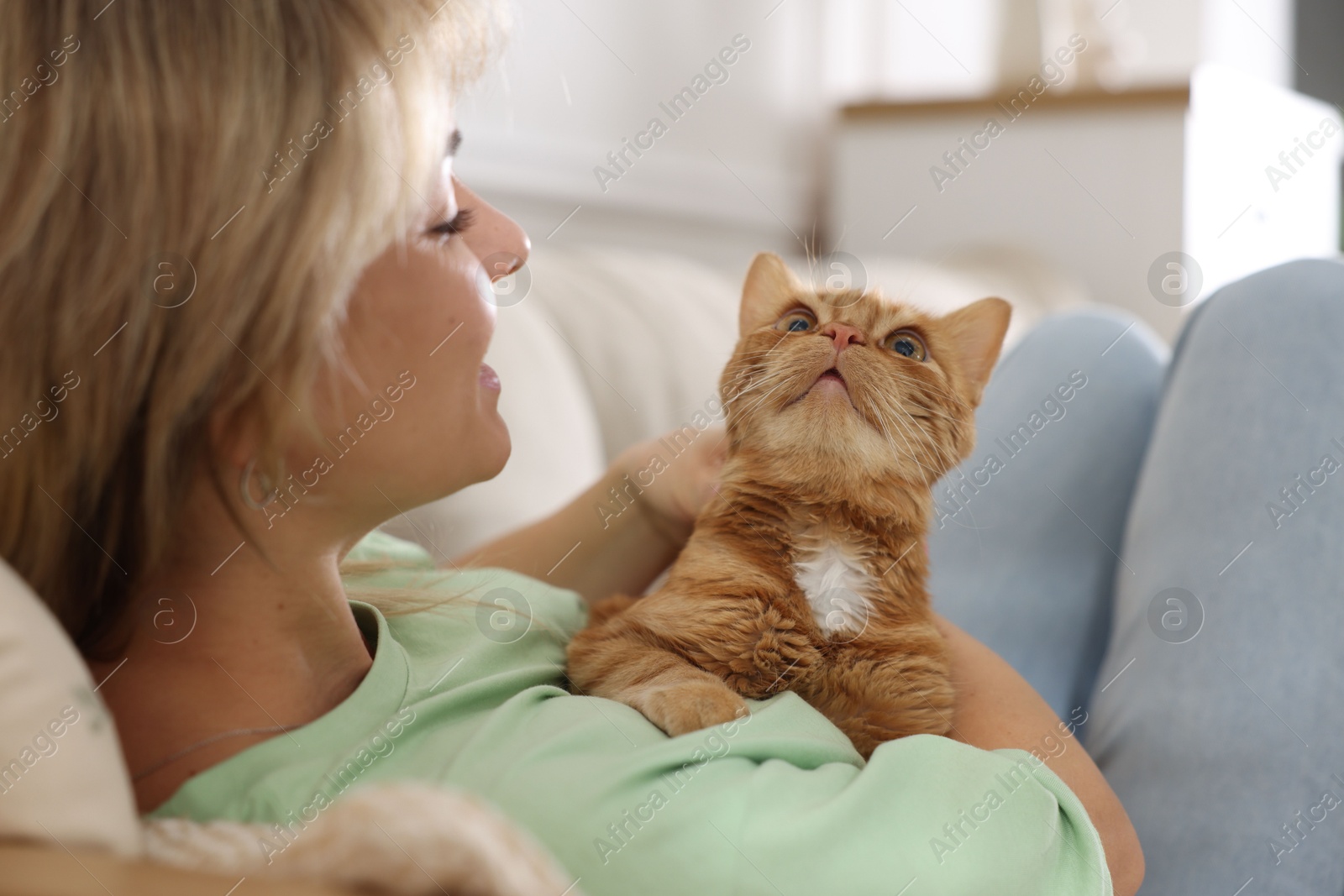 Photo of Woman with her cute ginger cat at home