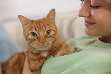 Photo of Woman with her cute ginger cat at home, closeup