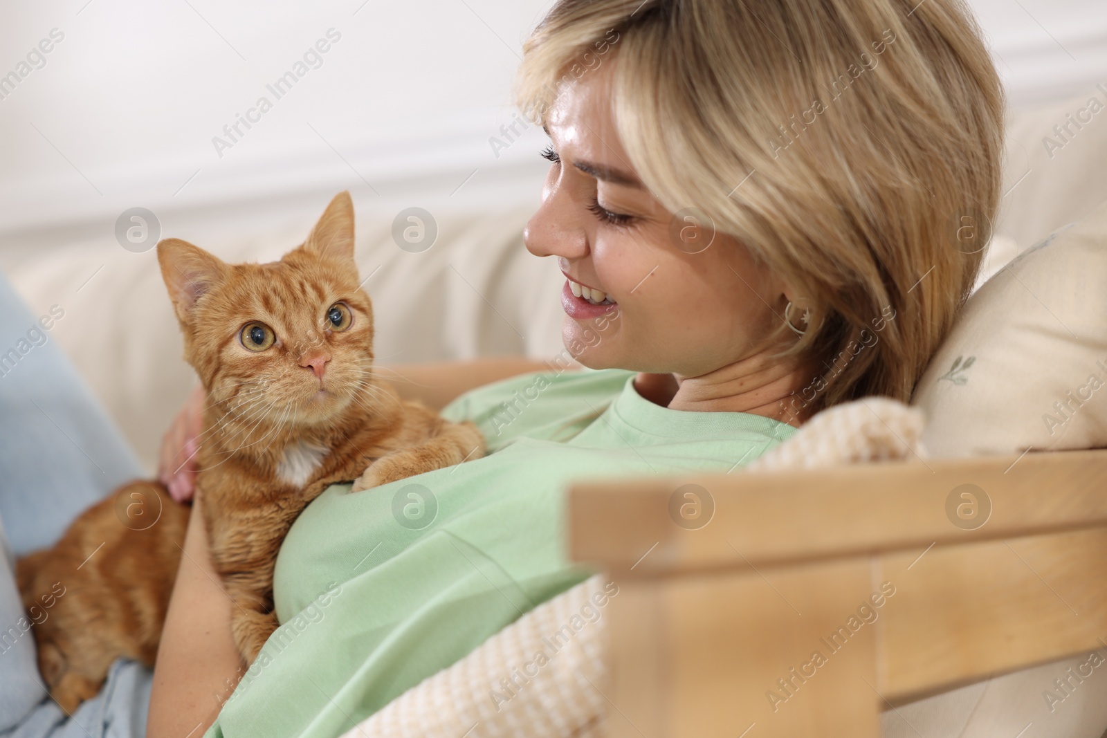 Photo of Woman with her cute ginger cat on sofa at home