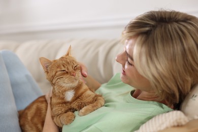 Photo of Woman with her cute ginger cat on sofa at home