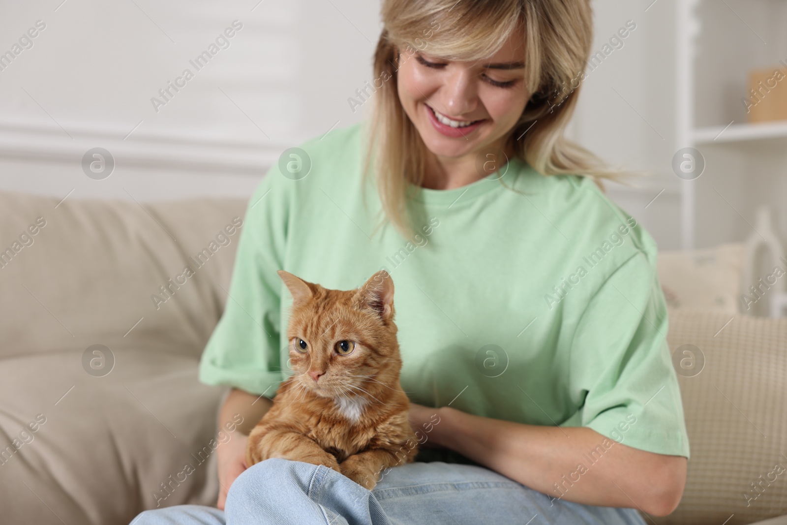 Photo of Woman with her cute ginger cat on sofa at home