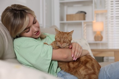 Photo of Woman with her cute ginger cat on sofa at home