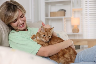 Photo of Woman with her cute ginger cat on sofa at home