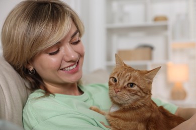 Photo of Woman with her cute ginger cat on sofa at home