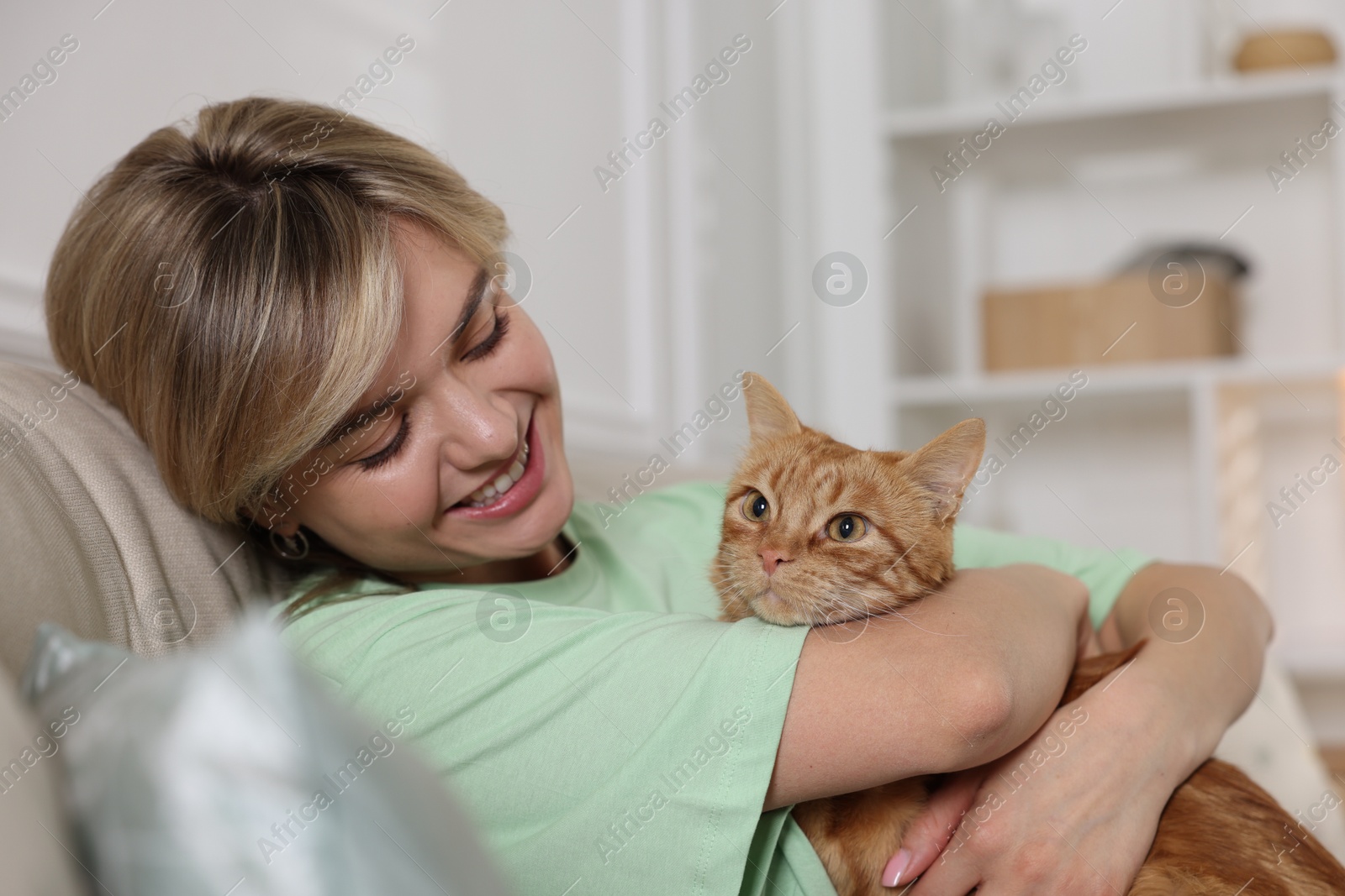 Photo of Woman with her cute ginger cat on sofa at home