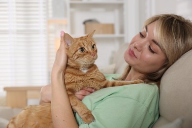 Photo of Woman with her cute ginger cat on sofa at home