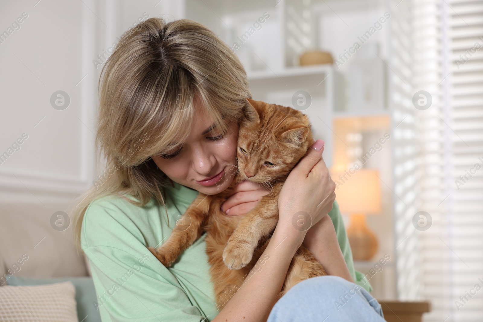 Photo of Woman with her cute ginger cat at home