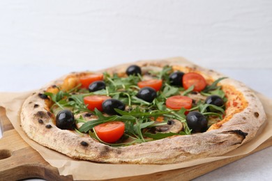 Photo of Tasty pizza with cherry tomatoes, black olives, mushrooms and arugula on white table, closeup