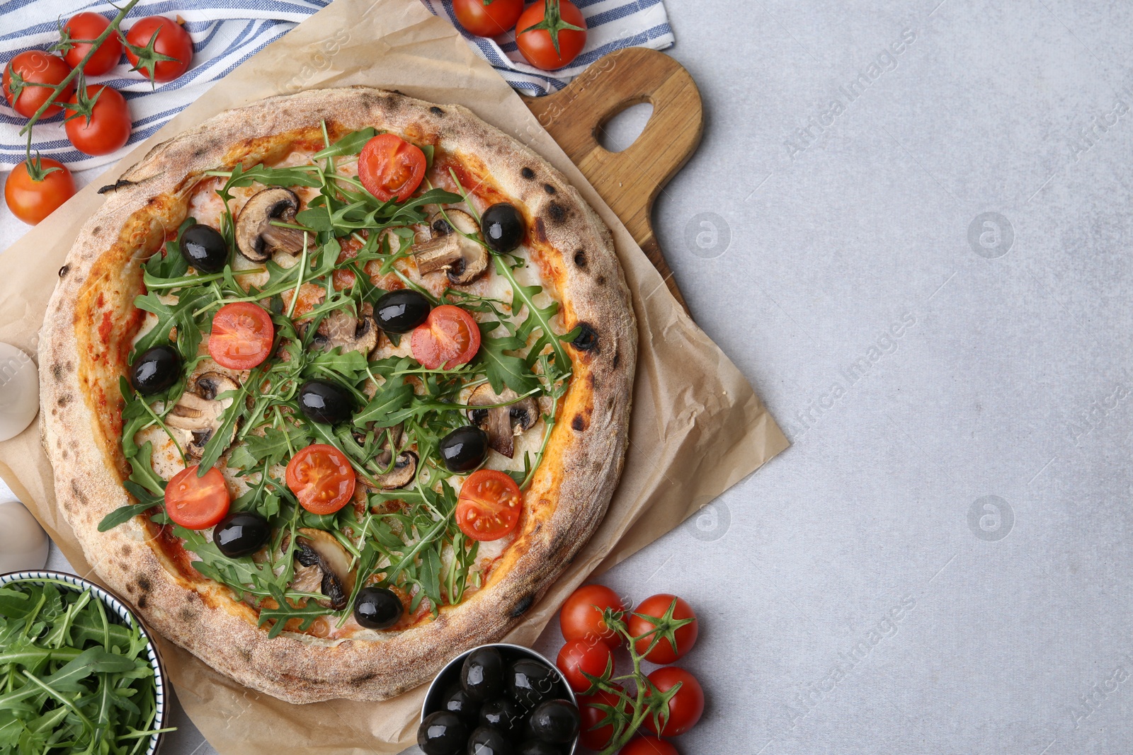 Tasty pizza with cherry tomatoes, black olives, mushrooms and arugula on light grey table, flat lay. Space for text Photo of Tasty pizza with cherry tomatoes, black olives, mushrooms and arugula on light grey table, flat lay. Space for text