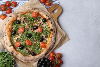 Photo of Tasty pizza with cherry tomatoes, black olives, mushrooms and arugula on light grey table, flat lay. Space for text