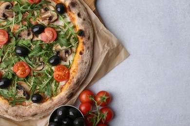 Photo of Tasty pizza with cherry tomatoes, black olives, mushrooms and arugula on light grey table, flat lay. Space for text