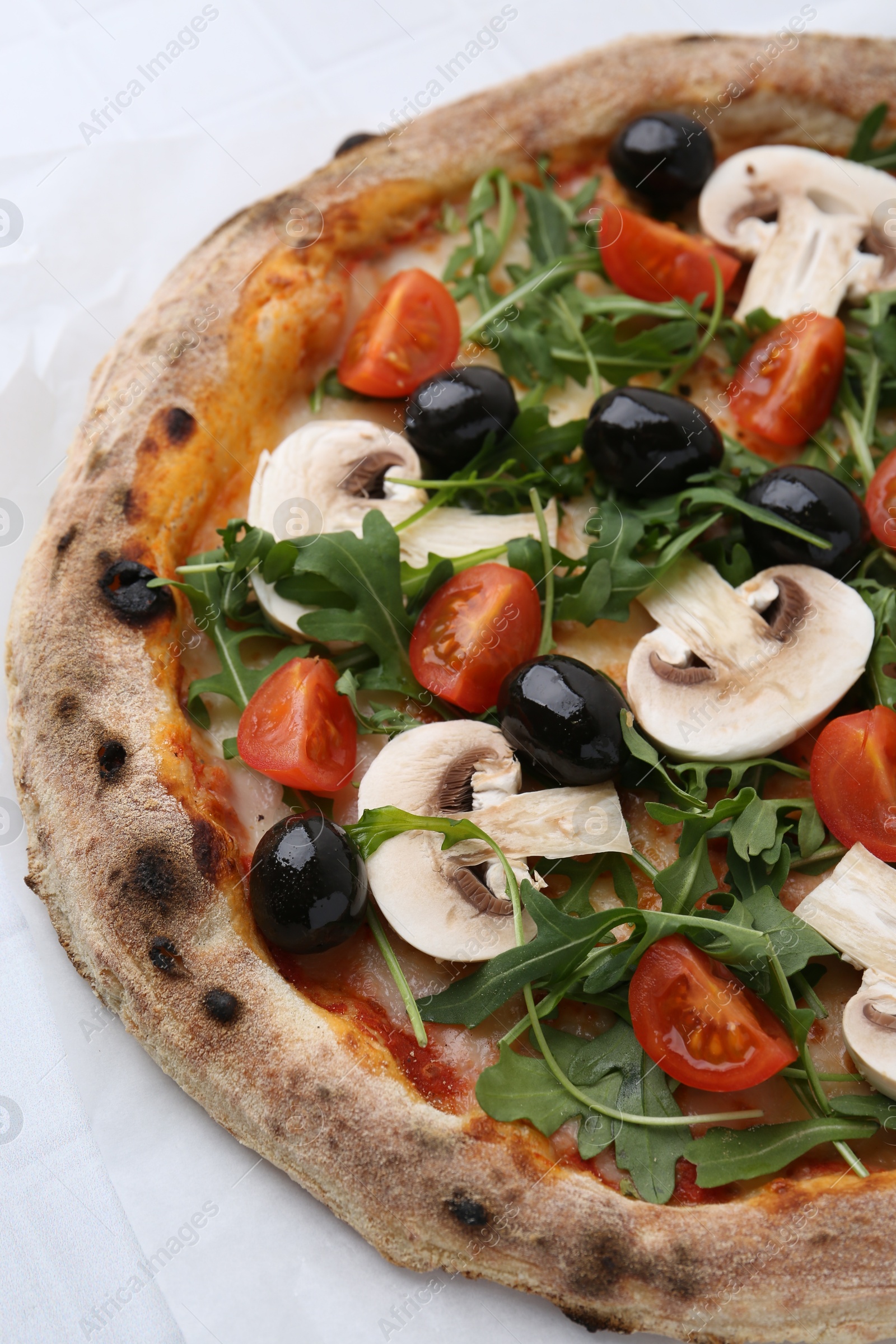 Tasty pizza with cherry tomatoes, black olives, mushrooms and arugula on white table, closeup Photo of Tasty pizza with cherry tomatoes, black olives, mushrooms and arugula on white table, closeup