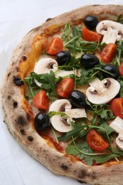 Photo of Tasty pizza with cherry tomatoes, black olives, mushrooms and arugula on white table, closeup