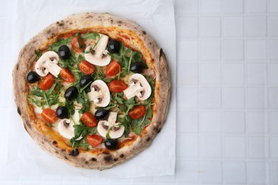 Photo of Tasty pizza with cherry tomatoes, black olives, mushrooms and arugula on white tiled table, top view. Space for text