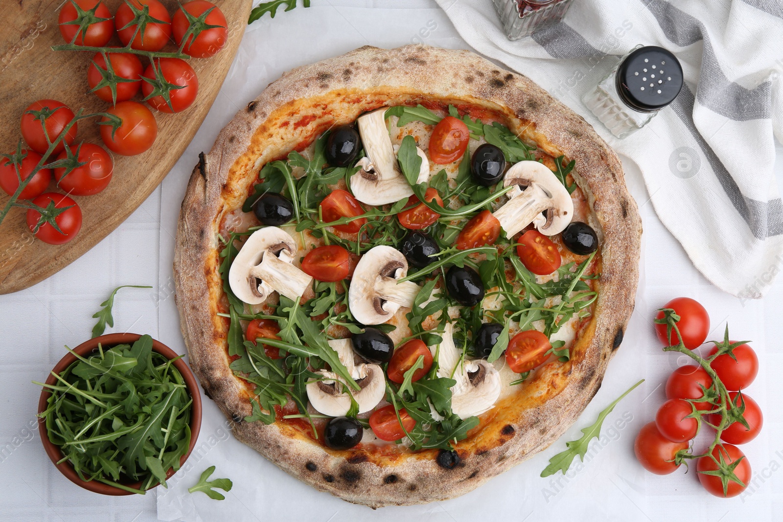 Tasty pizza with cherry tomatoes, black olives, mushrooms and arugula on white tiled table, flat lay Photo of Tasty pizza with cherry tomatoes, black olives, mushrooms and arugula on white tiled table, flat lay
