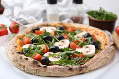 Photo of Tasty pizza with cherry tomatoes, black olives, mushrooms and arugula on white tiled table, closeup