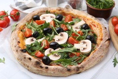 Photo of Tasty pizza with cherry tomatoes, black olives, mushrooms and arugula on white tiled table, closeup