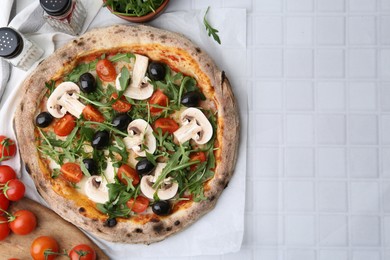 Photo of Tasty pizza with cherry tomatoes, black olives, mushrooms and arugula on white tiled table, flat lay. Space for text