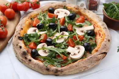 Photo of Tasty pizza with cherry tomatoes, black olives, mushrooms and arugula on white tiled table, closeup