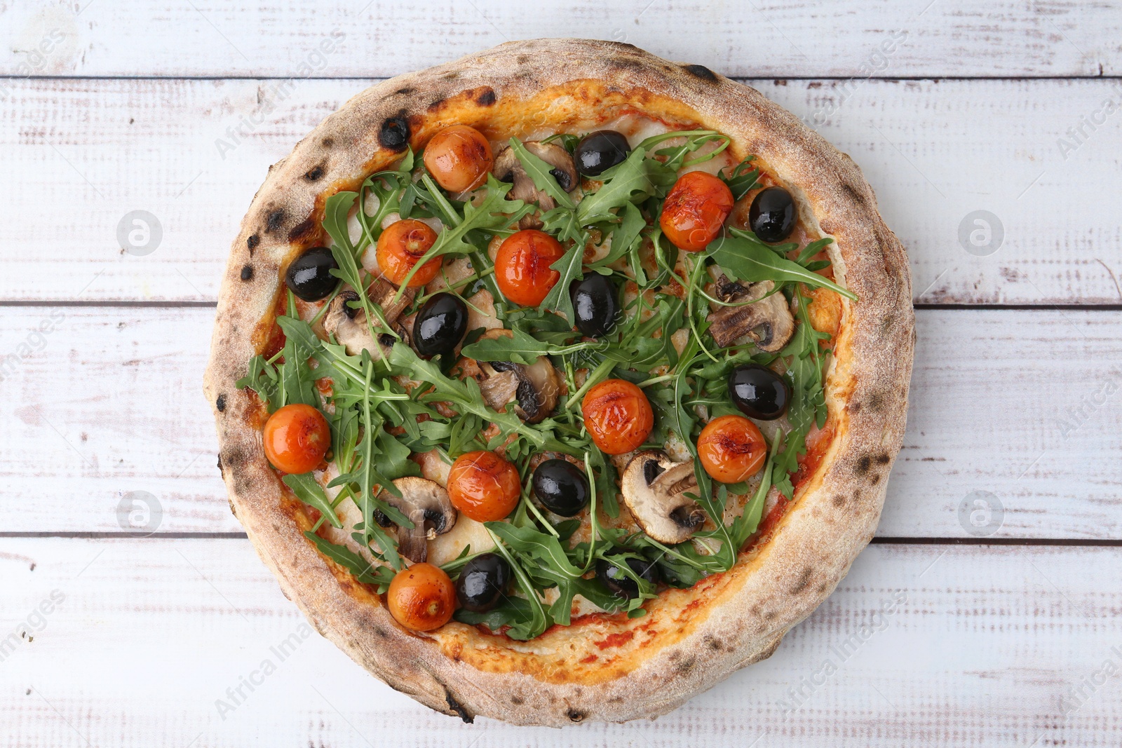 Tasty pizza with cherry tomatoes, black olives, mushrooms and arugula on white wooden table, top view Photo of Tasty pizza with cherry tomatoes, black olives, mushrooms and arugula on white wooden table, top view