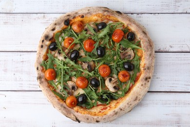 Photo of Tasty pizza with cherry tomatoes, black olives, mushrooms and arugula on white wooden table, top view