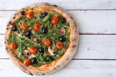 Photo of Tasty pizza with cherry tomatoes, black olives, mushrooms and arugula on white wooden table, top view. Space for text