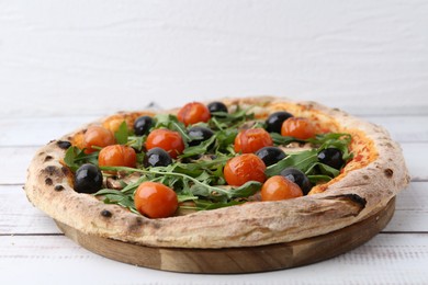 Photo of Tasty pizza with cherry tomatoes, black olives, mushrooms and arugula on white wooden table, closeup