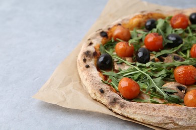 Photo of Tasty pizza with cherry tomatoes, black olives, mushrooms and arugula on grey table, closeup. Space for text