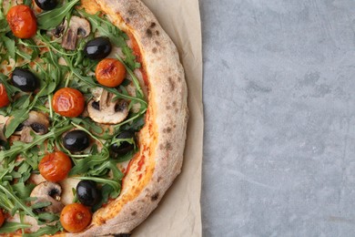 Photo of Tasty pizza with cherry tomatoes, black olives, mushrooms and arugula on grey table, top view. Space for text