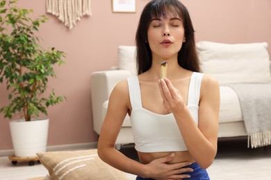 Photo of Woman with smoldering palo santo stick at home, space for text