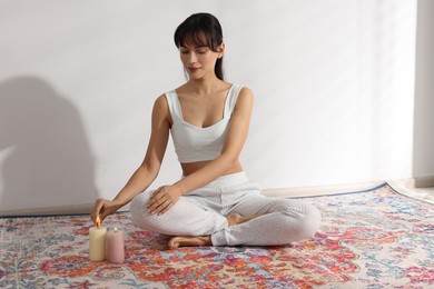 Photo of Woman lighting palo santo stick on floor at home