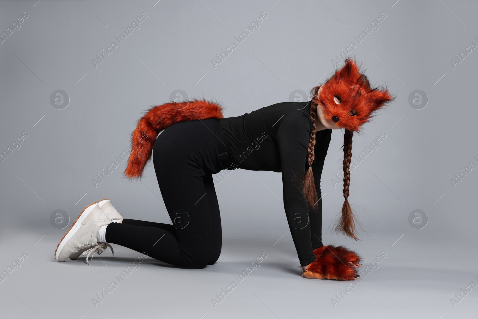 Photo of Quadrobics. Girl wearing fox mask, gloves and tail on grey background